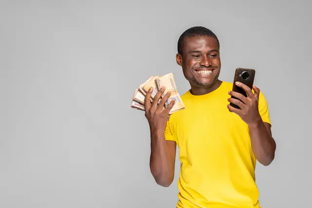 excited-young-black-man-holding-money-using-his-phone