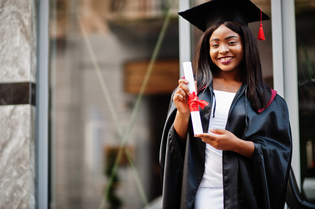 Young female african american student with diploma poses outdoor